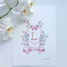 a card with the letter l on it next to some white flowers and a butterfly