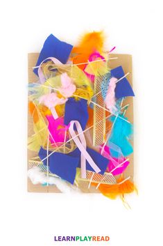 an art project with colored feathers and scissors on it, including yarns in the shape of ribbons