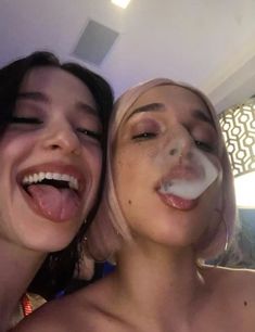 two women are smiling and one is sticking out her tongue