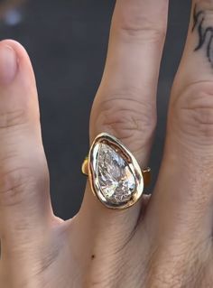 a close up of a person's hand with a ring on their finger and tattoos