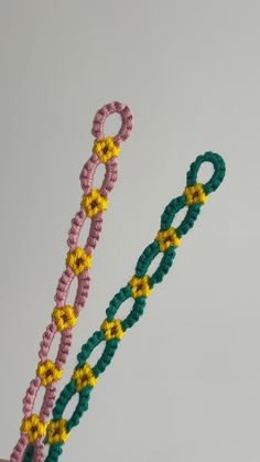 two crocheted bracelets are being held in the air