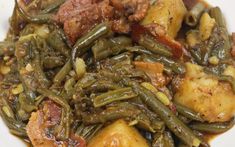 a white plate topped with green beans and potatoes