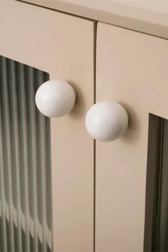 two white knobs on the side of a cabinet