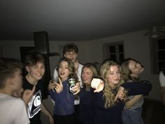 a group of young people standing around each other holding beer cans and pointing at the camera