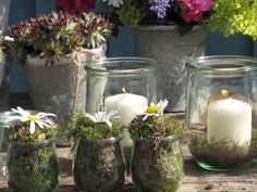 several glass jars filled with flowers and candles