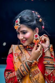 a woman in an orange and red sari with jewelry on her neck, smiling