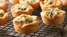 several muffins on a cooling rack with spinach and cheese in the middle