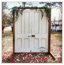 an open white door surrounded by flowers and petals on the ground in front of people