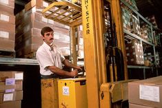 a man standing next to a forklift in a warehouse