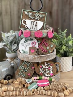 three tiered tray with cookies and coffee mugs on it, surrounded by other decorations