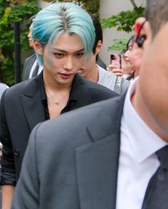 a young man with blue hair is surrounded by other people