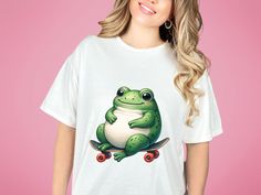 "Dive into the world of whimsy with our unique unisex t-shirt featuring a cute cartoon frog in a minimalist style, blissfully lying on a skateboard. This shirt blends playful charm with a sleek, modern design, making it perfect for anyone who loves unique and artistic clothing. Crafted for comfort and style, it's ideal for casual outings, skateboarding adventures, or simply as a trendy addition to your wardrobe. The shirt's design is not only eye-catching but also a conversation starter, appeali Frog Skateboard, Artistic Clothing, Cartoon Frog, Artist Outfit, Inspired Fashion, Minimalist Style, Family Shirts, Unisex Design, Minimalist Fashion