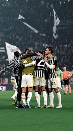 a group of soccer players huddle together on the field in front of an audience