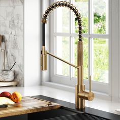 a kitchen sink with gold faucet and fruit on the counter