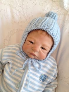 a baby wearing a blue and white striped outfit with a hat on it's head