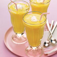 three glasses filled with orange juice on top of a pink plate