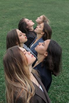 four women are laying on the grass and looking up