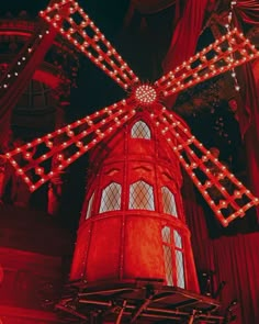 a large red windmill with lights on it's side