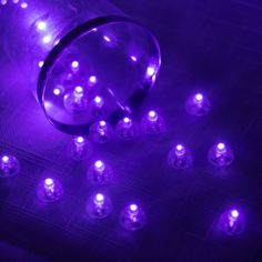 purple lights are shining in the dark on a black surface with small white dots around them