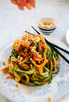 a plate full of noodles and vegetables with chopsticks next to it on a table