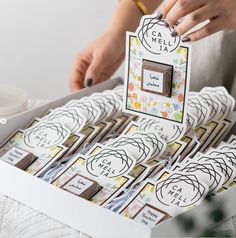 a person holding a box filled with lots of stickers on top of a table