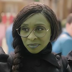 a woman wearing glasses and a green mask with long hair is posing for the camera