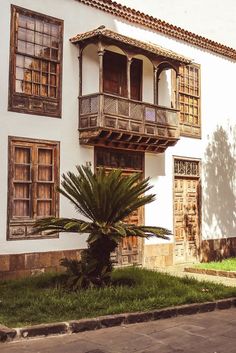 an old building with two balconies and a palm tree in the front yard