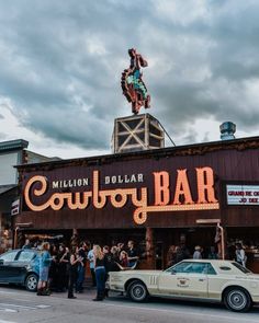 people are standing in front of a bar that is lit up with the word'cowboy bar '