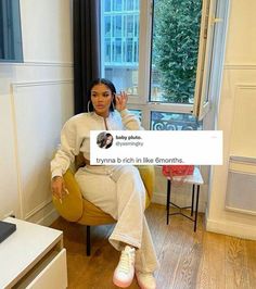 a woman sitting in a chair with her hand up to the camera and holding a tweet