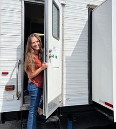 a woman standing in the doorway of a trailer with her hand on the door handle