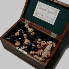 a wooden box filled with chess pieces on top of a table