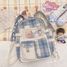 a blue and white plaid bag with patches on the front, two small dolls next to it