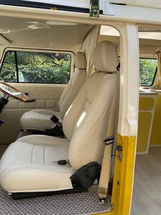 the interior of a vehicle with white leather seats and yellow trim on the front door