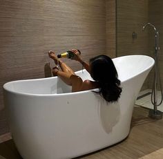 a woman sitting in a bathtub drinking from a bottle