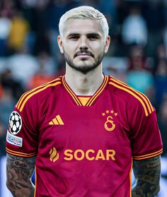 a man with white hair and tattoos on his face wearing a soccer uniform in front of a crowd