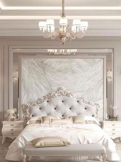 a white bed sitting under a chandelier next to a wall mounted mirror in a bedroom