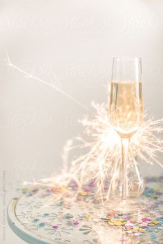 a glass of champagne sitting on top of a table with confetti around it