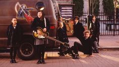 a group of children standing next to a van with an electric guitar in front of them