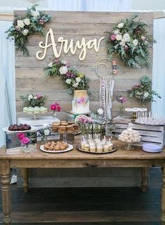 the dessert table is set up with flowers and cookies on it, along with an array of sweets