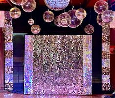 disco ball decorations hanging from the ceiling in front of a stage with chandeliers