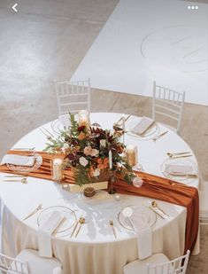 the table is set with white chairs and gold place settings for an elegant wedding reception