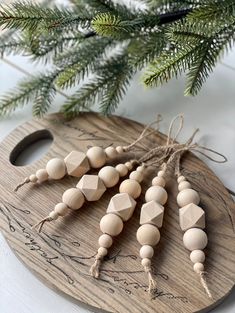 wooden bead ornaments on a cutting board next to a christmas tree branch with pine needles