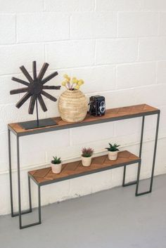 a table with two plants on it next to a wall