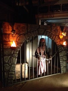 a man is standing in front of an iron gate with candles on the outside and inside