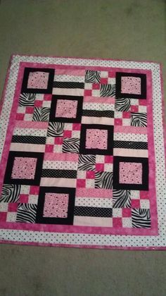 a pink and black quilt on the floor