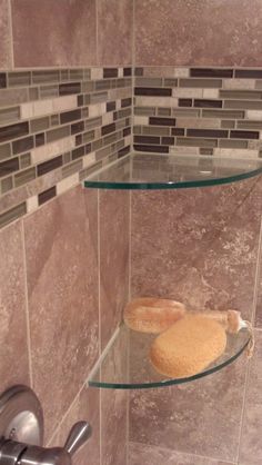 a glass shelf in the corner of a shower with a towel on top of it