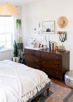 a bed room with a neatly made bed next to a window and a wooden dresser