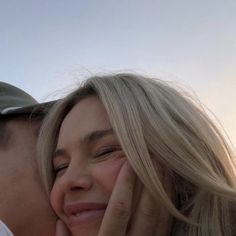 a man and woman kissing each other on the forehead with their hands near their face