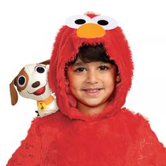 a young boy in a red costume holding a stuffed animal and smiling at the camera