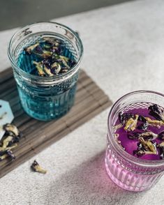 two jars filled with flowers sitting on top of a wooden tray next to each other